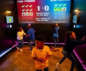 Kids in an interactive game room with screens. Beat the Bomb